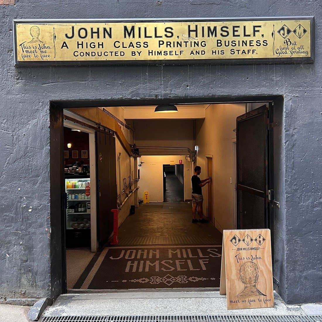 The heritage brass signage and mosaic entrance of John Mills Himself, a laneway café off Charlotte Street, Brisbane.